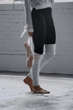 a woman in tights and ballet shoes is holding her feet up to the ground