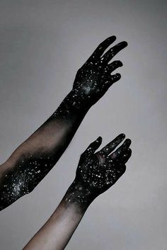 two hands with black paint on them reaching up into the air to touch each other