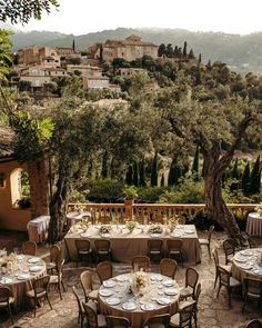 an outdoor dining area with tables and chairs set up in front of the mountainside