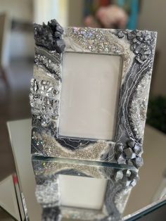 a glass table topped with a silver and black photo frame on top of a glass table