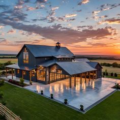 an aerial view of a large house with a pool in the middle and a sunset behind it