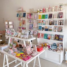 a room filled with lots of books on top of white tables and shelves full of books