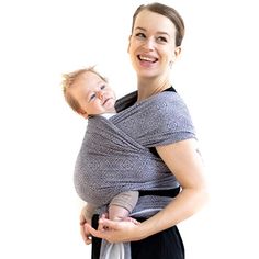 a woman holding a baby wrapped in a wrap on her chest and smiling at the camera