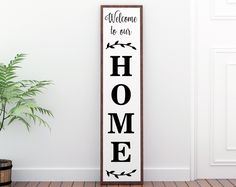 a wooden sign that says welcome to our home on the wall next to a potted plant