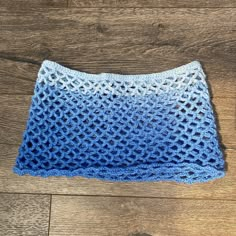 a blue and white crocheted blanket on top of a wooden floor