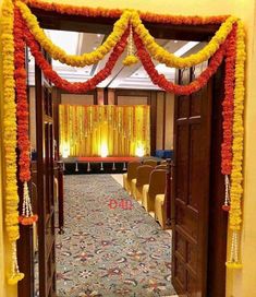 an entrance to a hall decorated with flowers and garlands for a wedding or other function