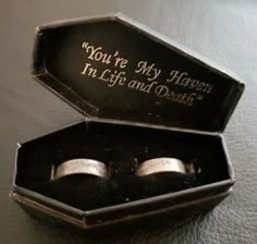 two wedding rings in a black box with writing on it