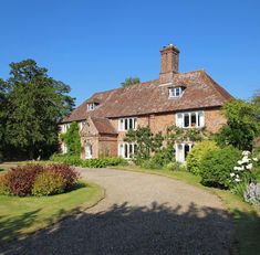 a large brick house surrounded by trees and flowers