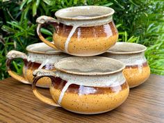 three brown and white mugs sitting on top of a wooden table