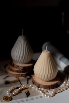 two white candles sitting on top of a table next to some pearls and other items