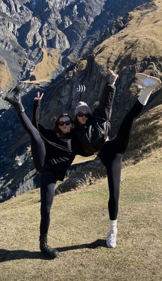 two women doing yoga on top of a mountain