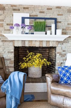 a living room with two chairs, a couch and a fire place in front of a brick fireplace