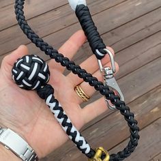 a hand holding two black and white braided leashes with gold hardware clasps