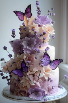 a three tiered cake with purple butterflies on the top and lavender flowers on the bottom