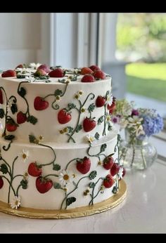 a three layer cake decorated with strawberries and daisies