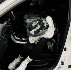 a woman sitting in the back seat of a car with flowers on her shirt and purse