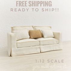 a white couch sitting on top of a wooden floor next to a sign that says free shipping ready to ship