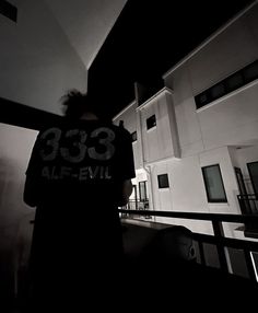 black and white photograph of a person standing in front of a building with the number thirty three on it