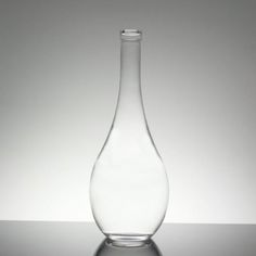 a clear glass vase sitting on top of a reflective surface with no one around it