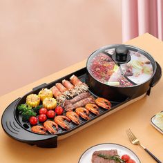 a grill with various foods on it sitting on a table next to plates and utensils