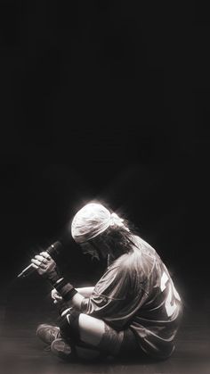 a black and white photo of a person sitting on the ground with a microphone in their hand