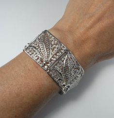 Here is an exceptional Art Nouveau completely handmade silver filigree bracelet circa 1890. The workmanship here is reminiscent of 18th century filigree in the quality and intricacy of this amazing piece. Each panel is entirely made by hand with silver wire twisted and wound into a fern and frond design each bouquet tied with a feminine bow. Amazingly each panel is not flat but the silver lace design is raised in relief with the central fern frond sitting higher to the rest of the panel. When th Antique Cuff Bracelet With Intricate Design For Formal Occasions, Wedding Filigree Bangle Bracelets, Elegant Bangle Bracelet With Decorative Band, Elegant Etched Bangle For Wedding, Victorian Cuff Bracelet With Intricate Design For Ceremonial, Victorian Cuff Bracelet With Intricate Design, Victorian Cuff Bracelet With Intricate Design For Ceremonial Occasions, Victorian Style Ceremonial Cuff Bracelet With Intricate Design, Victorian Cuff Bracelet With Intricate Design For Formal Events