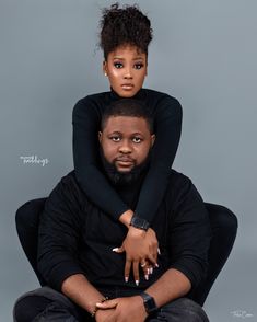 a man and woman sitting on top of each other in front of a gray background