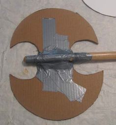 an unfinished piece of cardboard with a wooden handle and metal parts on it, sitting on top of a table