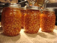 three jars filled with beans sitting on top of a table next to a stovetop