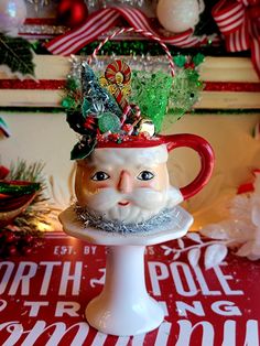 a santa clause mug with candy canes and decorations on it sitting on a pedestal