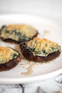 three stuffed mushrooms on a white plate with parmesan cheese