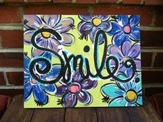 a painting with the word smile painted on it sitting on top of a wooden table