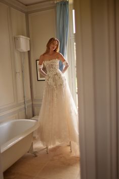 a woman in a wedding dress standing next to a tub