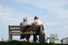 two people sitting on a bench looking at the city