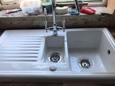 a white sink sitting under a window next to a window sill with toothbrushes on it