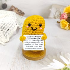 a small crocheted doll holding a sign that says,'emotial support chicken negget '