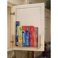 the kitchen cabinet door is open and has several cans on it, as well as an overhead spice rack