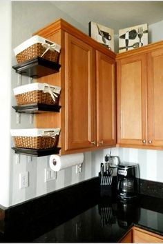 a kitchen with wooden cabinets and black counter tops, baskets on the wall above the stove