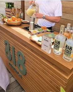 a man pouring orange juice into a glass on top of a wooden counter next to bottles