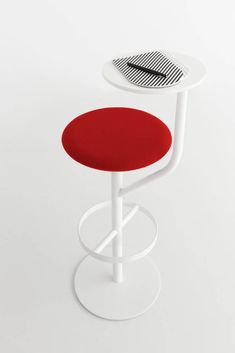 a red and white stool sitting next to a small table with a hat on it