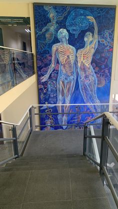 a large painting on the wall in a building with glass railings and handrails