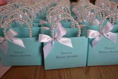 small blue boxes with pearls and bows on them are sitting on a table in front of other boxes