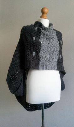 a white mannequin wearing a gray and black knitted ponchy with polka dots