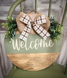 a welcome sign with a bow on it sitting in a green chair next to a wall