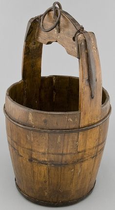 an old wooden bucket with a handle on the top and handles hanging from it's sides