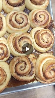 a pan filled with cinnamon rolls on top of a wooden table