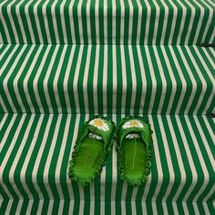 a pair of green slippers sitting on top of a set of striped carpeted steps