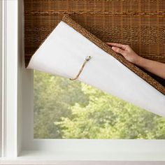 a person is pulling up the blinds in front of a window with an open roller shade