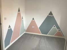 an empty room with mountains painted on the wall and carpeted flooring in front of it