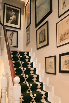 the stairs are decorated with black and white rugs, framed by pictures on the wall